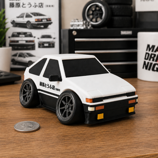 Anime-inspired tofu shop drift hatchback tooned 3D printed desk model displayed on a workshop desk beside a US quarter for scale.