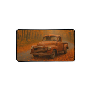 Medium 12×22 inch desk mat printed with a rust-colored vintage truck under golden fall trees, shown with soft rounded corners.