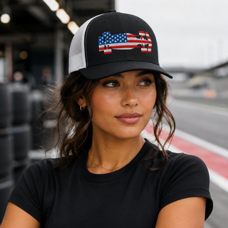 Woman wearing a black and white USA flag formula racing car embroidered snapback trucker cap in a racetrack pit lane