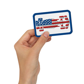 USA flag formula racing car embroidered patch held in hand against a white background.