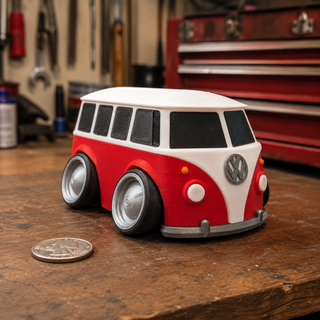Red and white Volkswagen T1 Bus tooned 3D printed desk model displayed on a garage workbench, shown next to a U.S. quarter for scale.